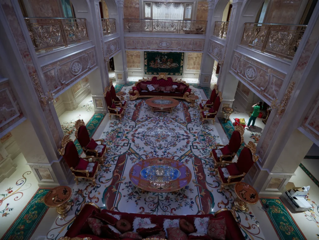 Large marble inlay floor with multicolored floral medallion and borders in a double-height luxury interior.