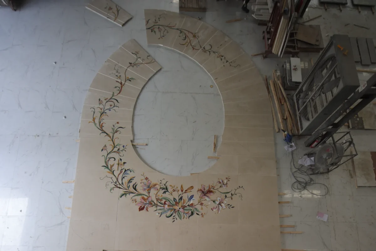 Curved marble inlay panel with floral pietre dure motif in a workshop.
