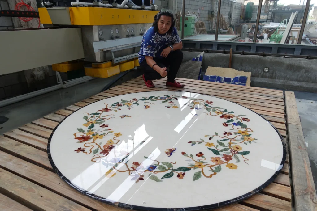 Large circular marble inlay medallion with floral pietre dure design in a workshop.