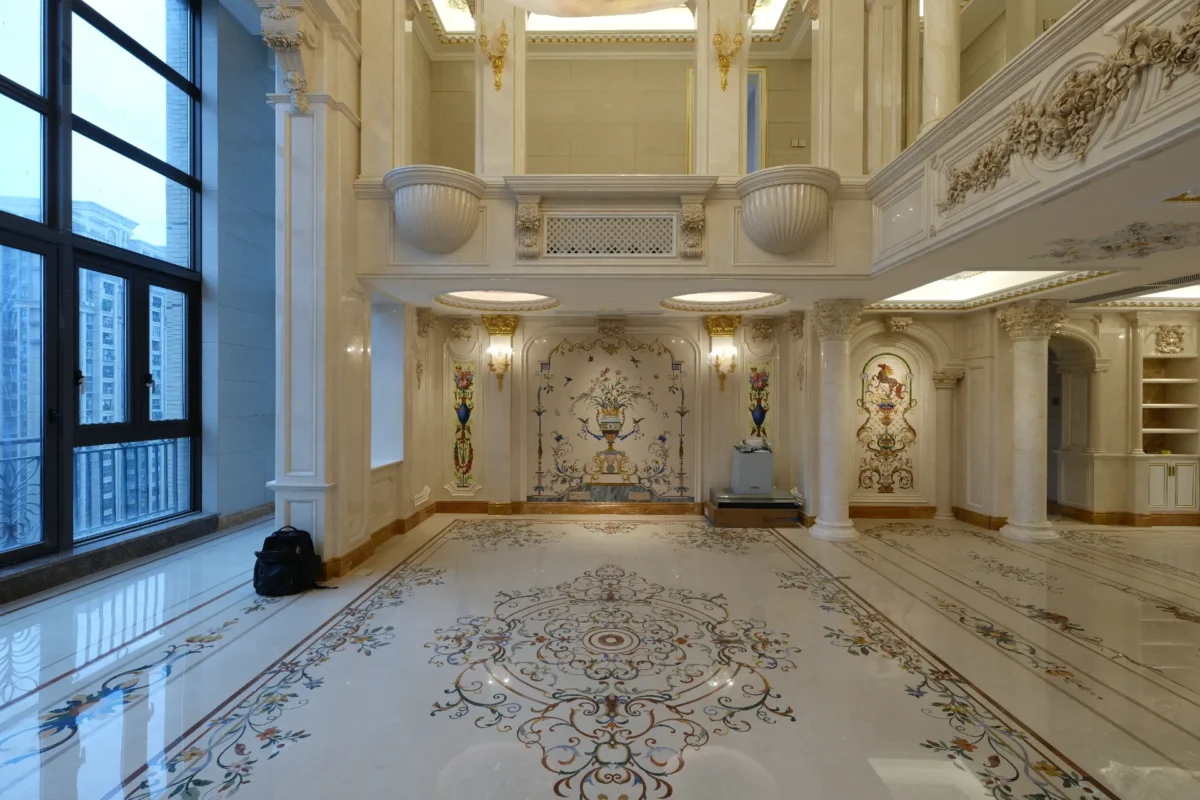 Polished marble floor with floral inlay, wall panels, and columns in a luxury double-height hall.