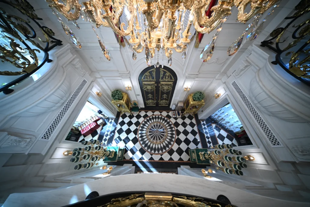 Black and white checkered marble floor with a central waterjet medallion in a grand white interior.